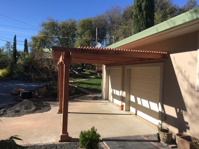 Finished timber-frame pergola over a driveway and garage entry