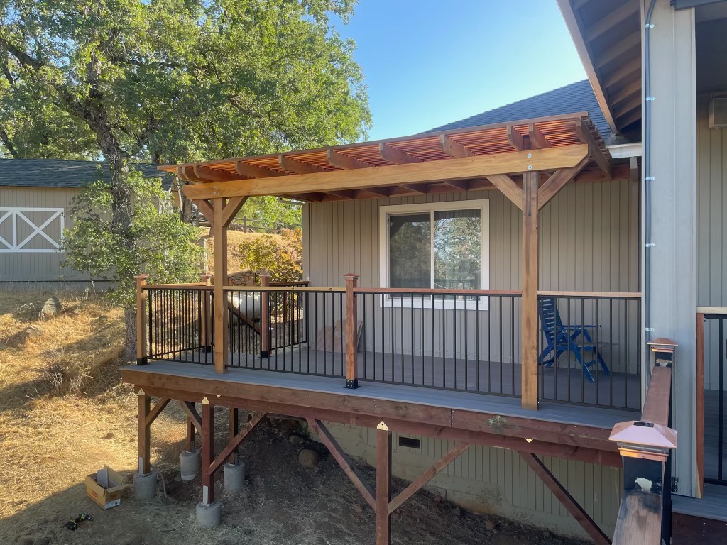 Small covered deck with timber-frame awning off the back of a home