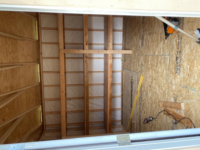 Inside a finished shed — built-in shelving and framed walls