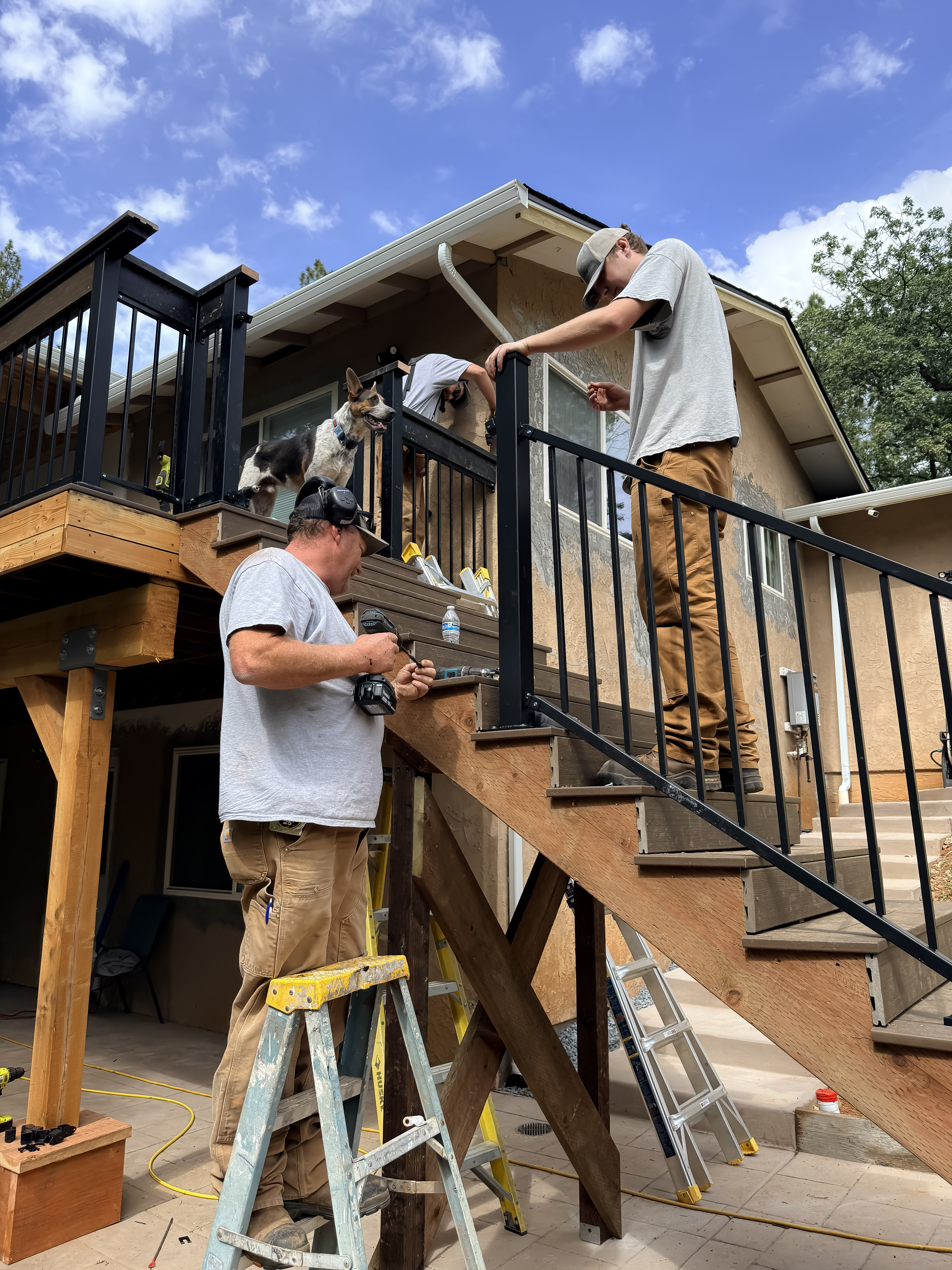 Crew installing railing on deck adjacent to covered patio